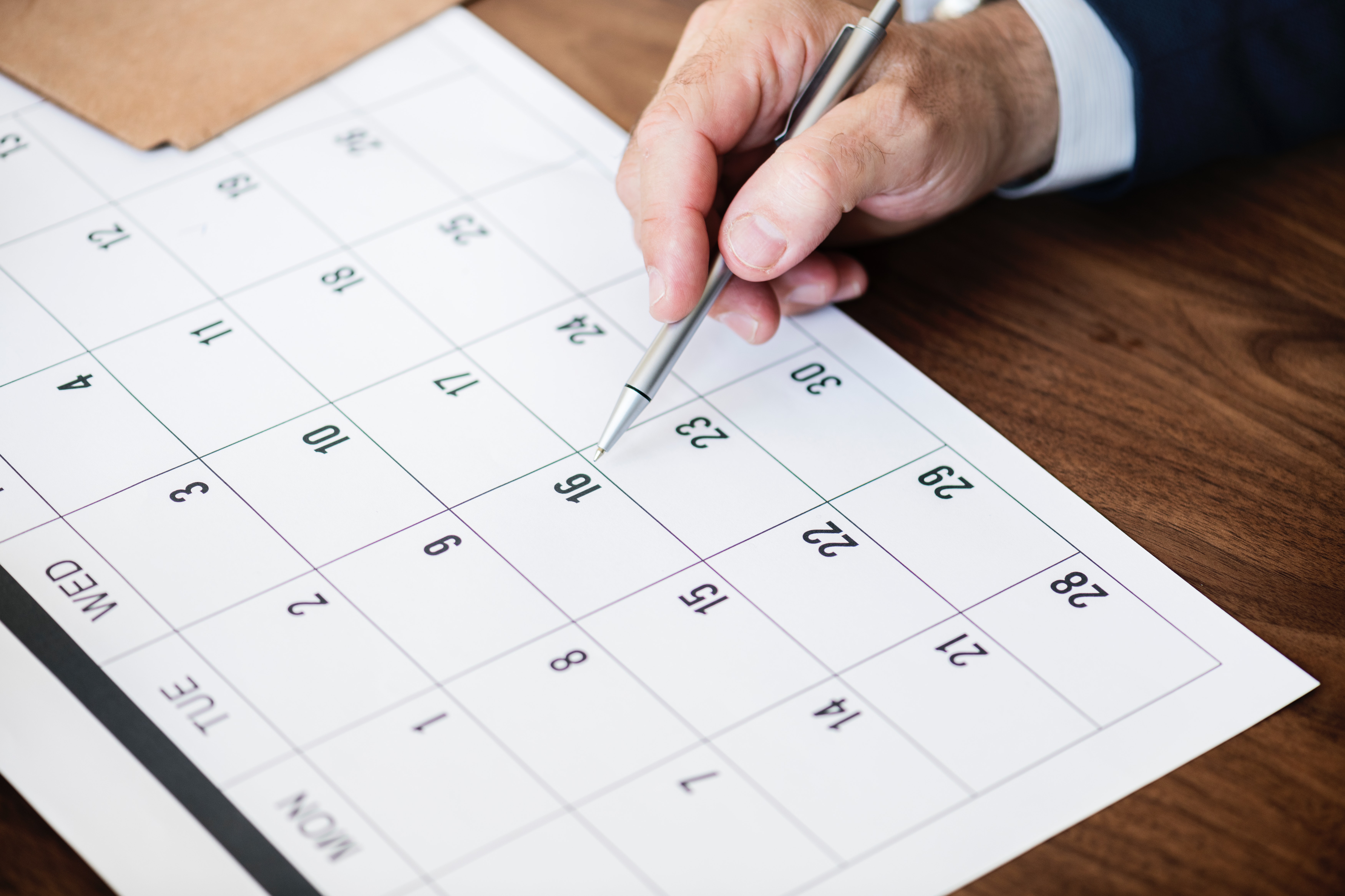 Person Pointing at Calendar with Pen